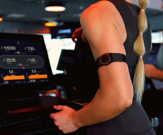 Person running on a treadmill wearing an OTconnect Beat.